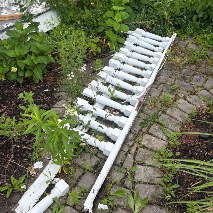 Old broken railing sitting in a garden bed before removal